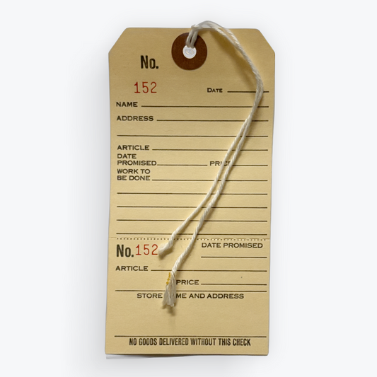 A vintage-style paper inventory tag with a hanging string, printed with fields for number, name, address, article, date promised, and price, shown on a plain light background.