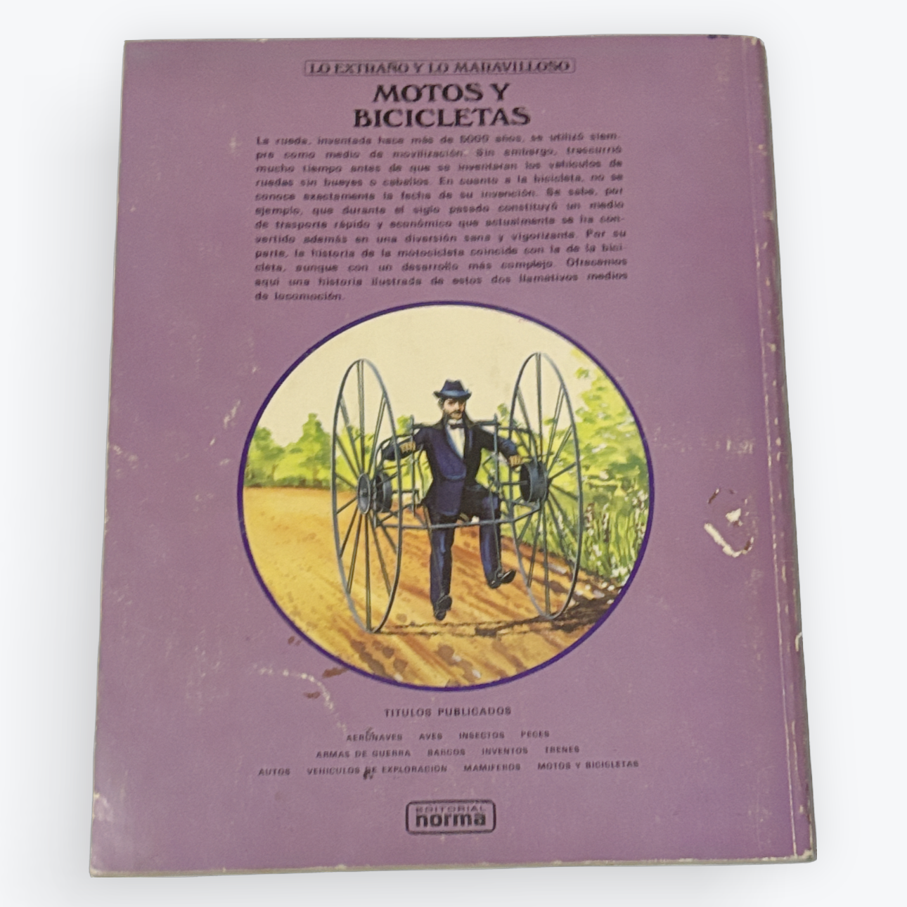 A vintage Spanish book titled 'Los Leones y la Barbilla: Motos y Bicicletas' with a dusty purple cover, featuring a circular illustration of a man riding a large wheeled vehicle.